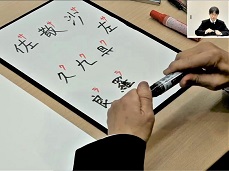 A lecturer writing letters on Japanese writing paper for calligraphy